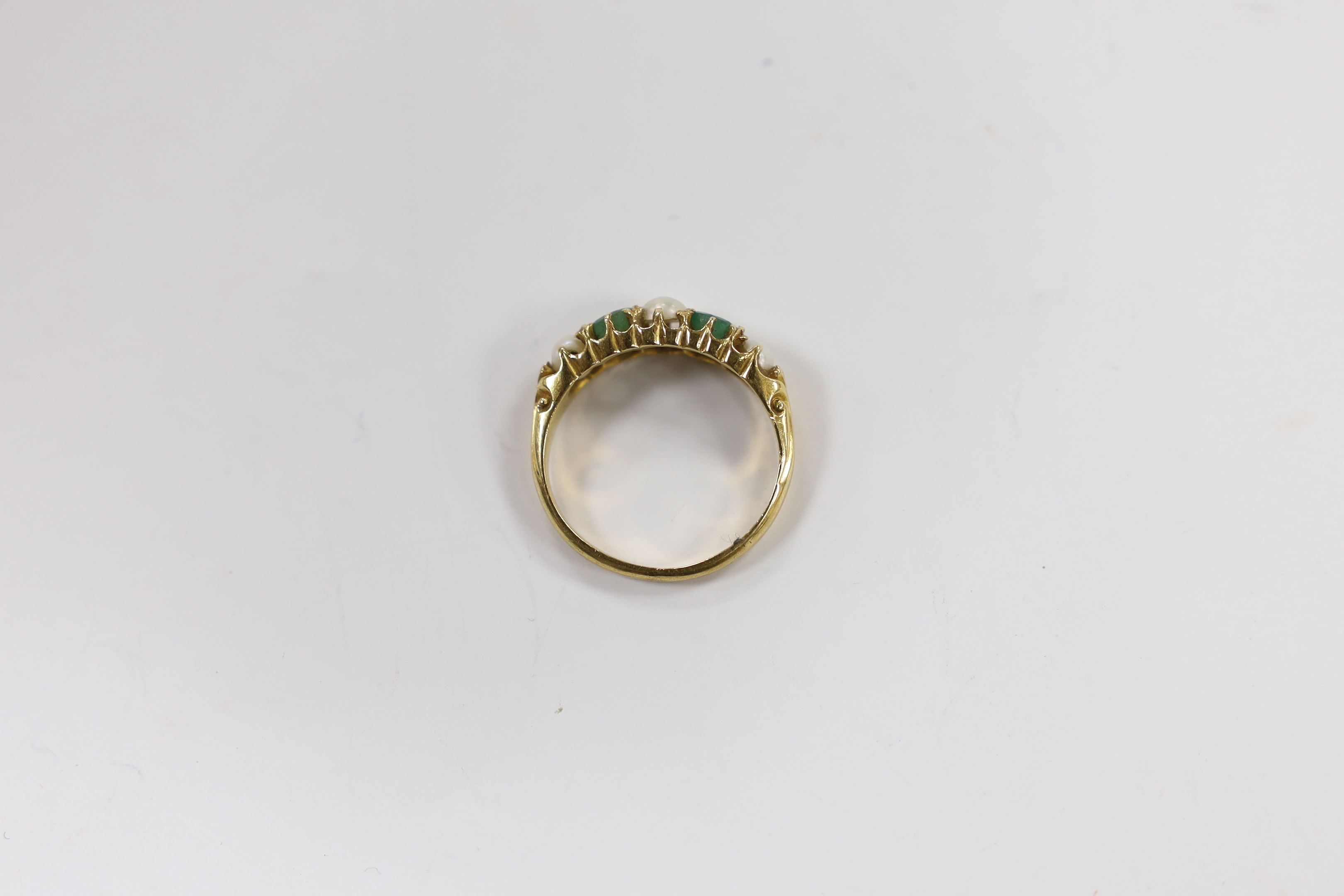 An 18ct, two stone emerald and three stone split pearl set half hoop ring, size P, gross weight 4.1 grams.